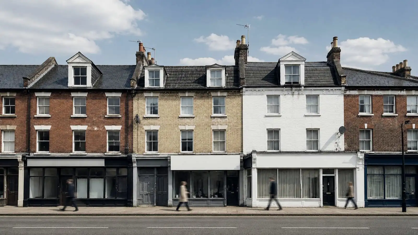 A row of British high street buildings, shops at street level with flats above